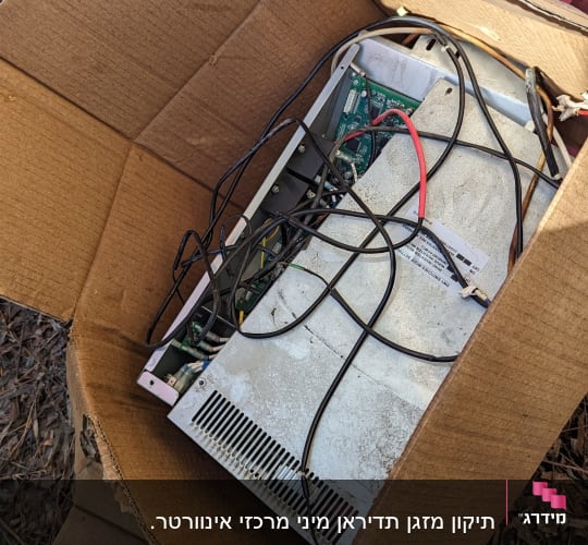 יחידת מיזוג אוויר ישנה עם חוטים בתוך קופסת קרטון